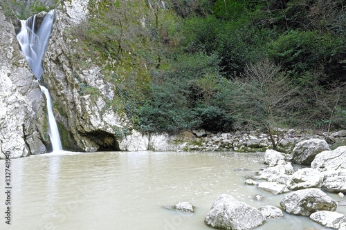 waterfall in spring in a wild gorge surrounded by young foliage photo