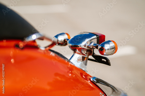 Closeup chrome detail and taillight and turn signals of orange retro vintage scooter.