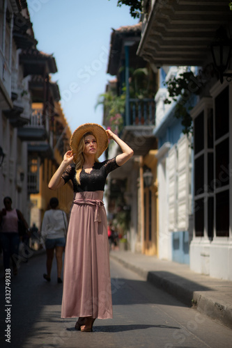 Beautiful woman with long dress walking alone at the colorful streets of the colonial walled city of Cartagena. Colombia © Hladchenko Viktor