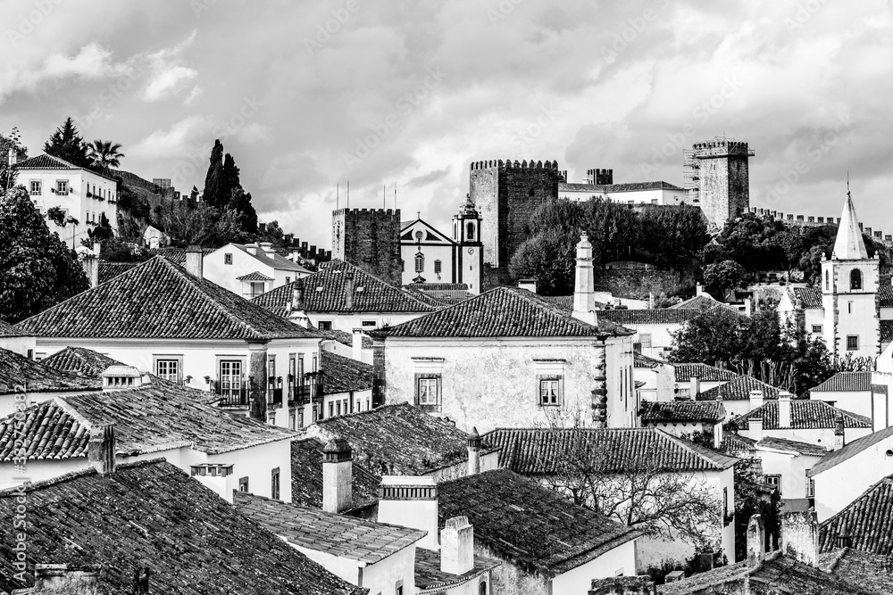 Old town skyline of Obidos, Portugal with house roof tops, church towers and the wall of the medieval castle located in the civil parish of Santa Maria, São Pedro e Sobral da Lagoa, Oeste region