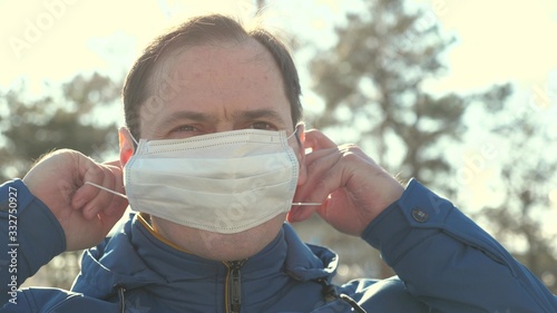 Flu pandemic. a man puts on a medical protective mask on a street in a city. close-up. health and safety concept, coronavirus N1H1, virus protection. health and safety concept.