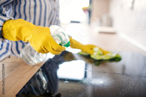 Unrecognizable senior woman cleaning kitchen counter indoors at home.