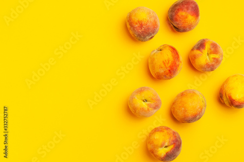 Summer fruit background. Flat lay composition with peaches. Ripe juicy peaches with green leaves on yellow background. Flat lay top view copy space. Fresh organic fruit, vegan food. Harvest concept