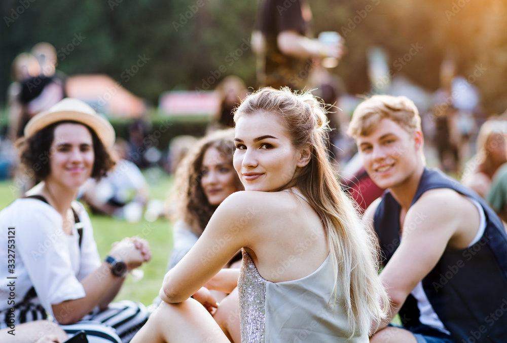 Group of young friends sitting on ground at summer festival. Group of young friends sitting on ground at summer festival.