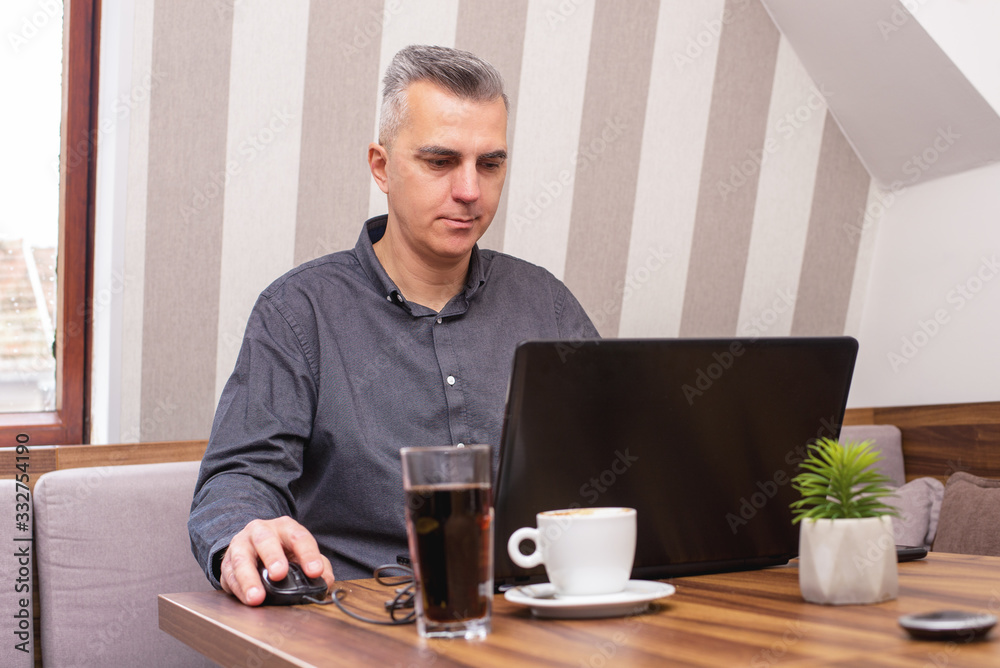 Businessman having coffee in a cafe while working on laptop Businessman having coffee in a cafe while working on laptop