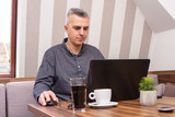 Businessman having coffee in a cafe while working on laptop