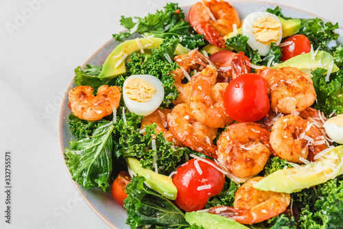 Healthy shrimp caesar salad with avocado, parmesan cheese, tomatoes and kale on white background. close up