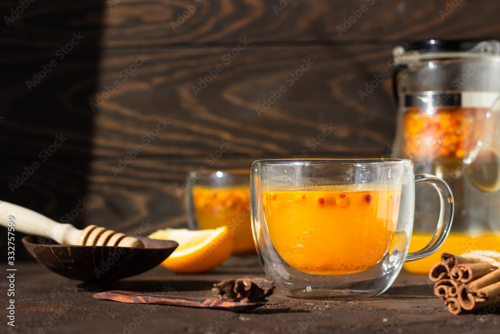 Φωτογραφία Colorful hot spicy sea buckthorn tea with cinnamon, anise and honey in glass cup on dark brown concrete background, selective focus