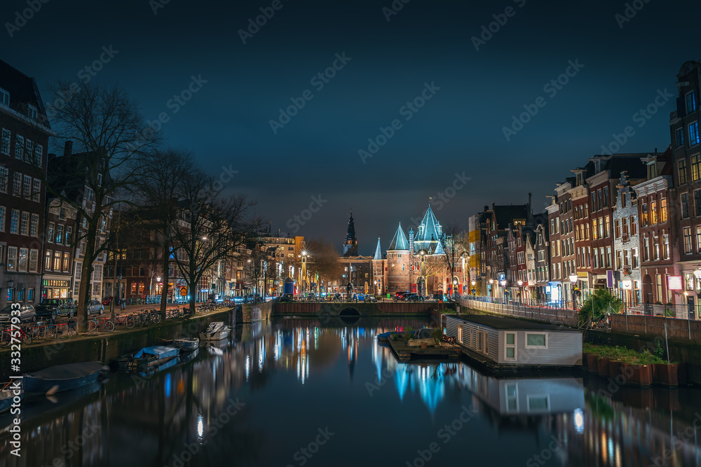 Canal of Amsterdam at night with beautiful old buildings, bridge and water reflection, Netherlands.