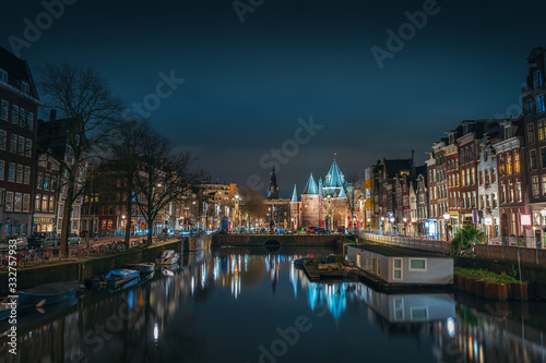 Canal of Amsterdam at night with beautiful old buildings, bridge and water reflection, Netherlands.