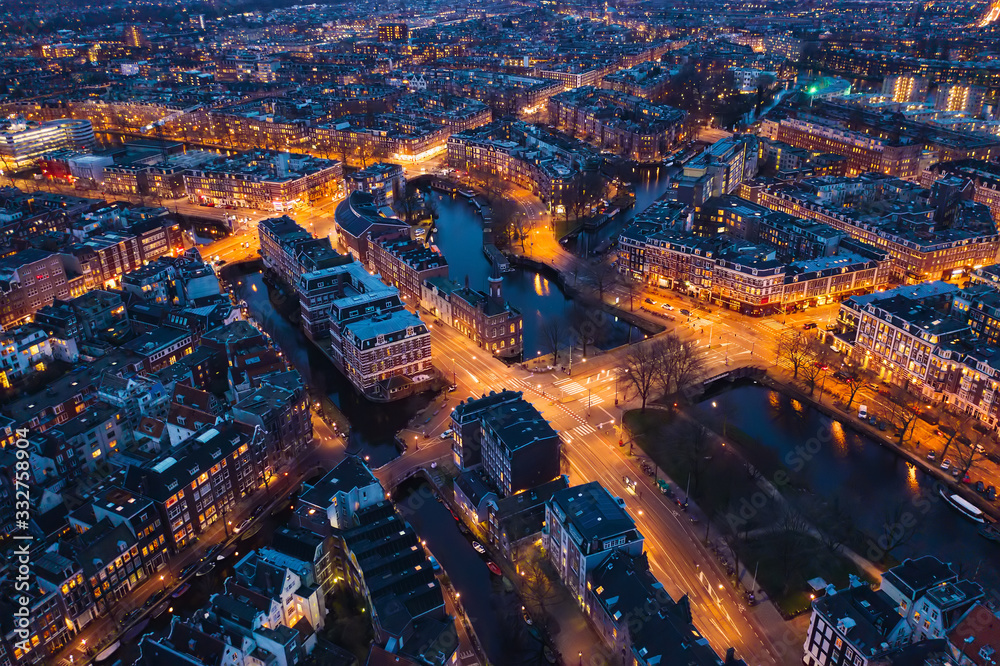 Amsterdam Netherlands aerial view at night. Old dancing houses, river Amstel, canals with bridges, old european city landscape from above.