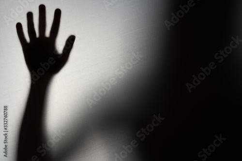 Blurred Woman's hand shadow asking for help. Horror and domestic violence concept