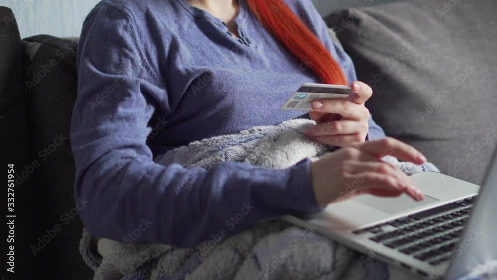 A young woman in a protective mask makes online purchases while being quarantined during the coronavirus epidemic. Close up of hands. A young woman in a protective mask makes online purchases while being quarantined during the coronavirus epidemic. Close up of hands.