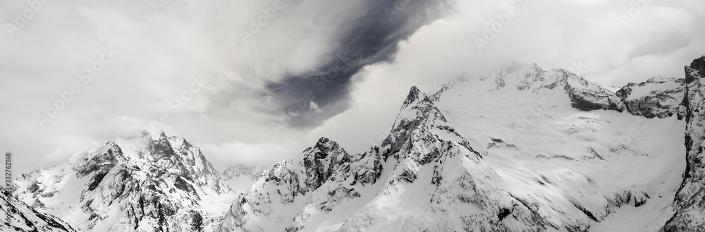 Panorama of gray high mountain peaks covered with ice