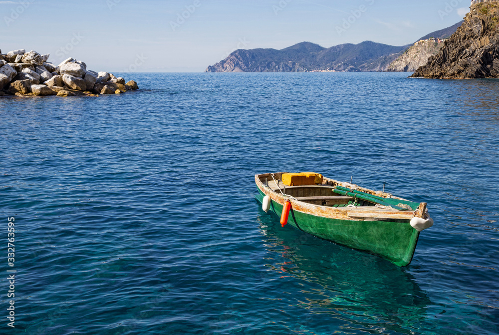 sea view with green boat and rock on background in Italy