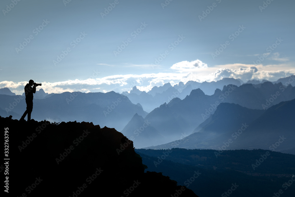 Panorama of mountains after sunset with silhouette of man intent on photographing.