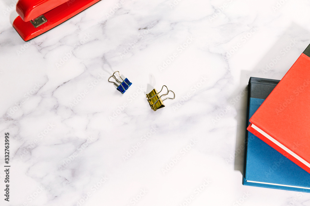 Naklejka premium Office work desk flat lay with books, paper clips, and stapler on marble surface with copy space