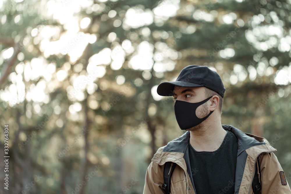 portrait of man in medical mask on the trees background