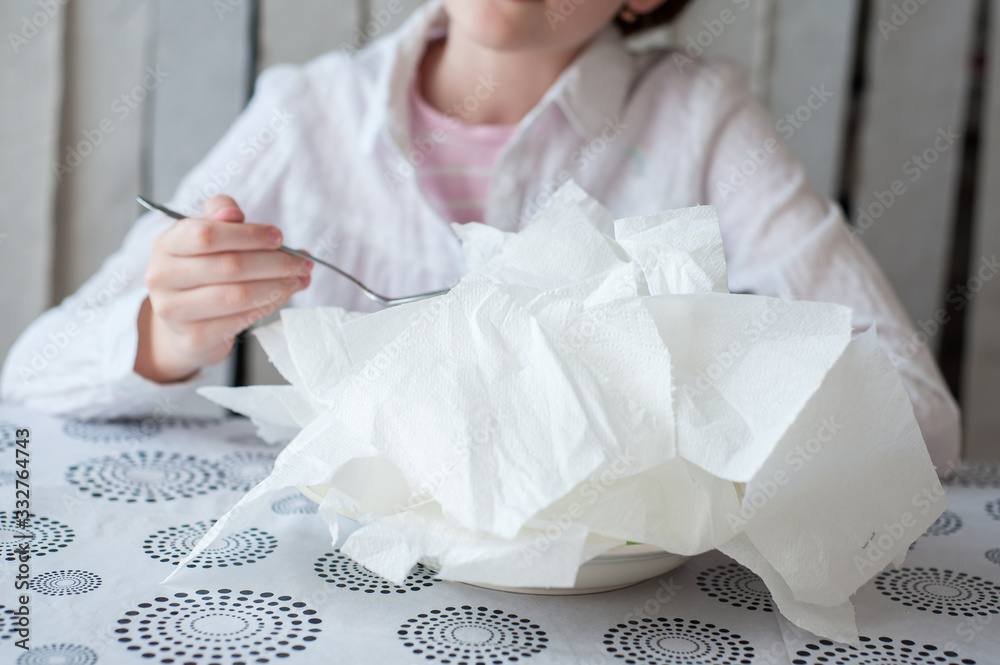 Pieces of toilet paper lie on a plate. Girl wants to eat it with a spoon Pieces of toilet paper lie on a plate. Girl wants to eat it with a spoon