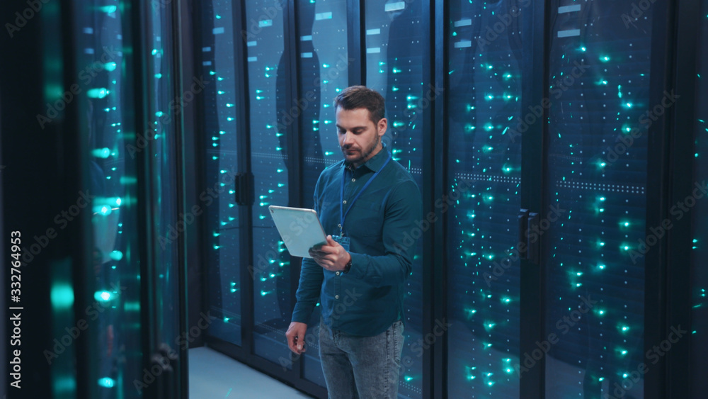 IT professional with digital tablet monitoring system performance of  database network servers working on rack in high tech data center.  Webhosting, cloud computing. Stock-Foto | Adobe Stock