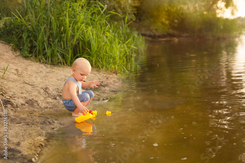 a boy plays with toy ducks in the water. a child bathes in water