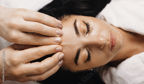 Upper view portrait of a caucasian woman lying and having a spa session of facial massage