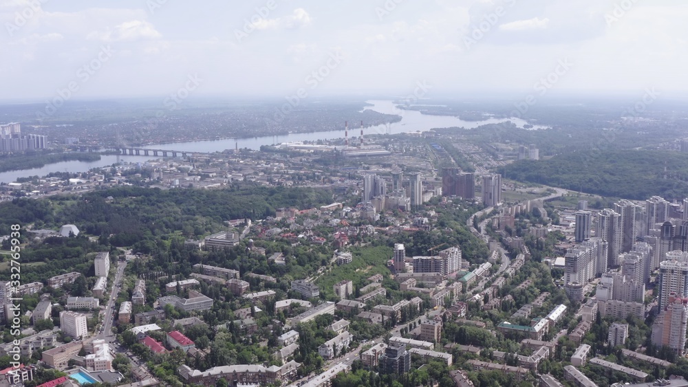 smooth drone take-off up over the summer streets of the green city (Kiev) against the background of the big river (Dnipro) Ukraine