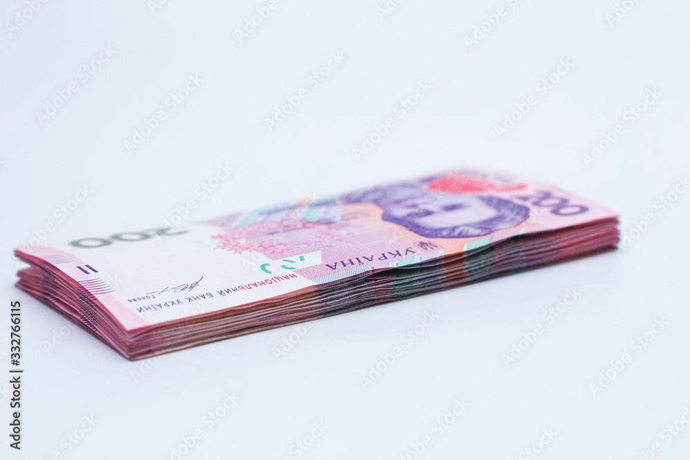 A lot of new banknotes in denominations of 200 Ukrainian hryvnias isolated on a white background with shadow. European money exchange. Ukraine currency. Selective focus A lot of new banknotes in denominations of 200 Ukrainian hryvnias isolated on a white background with shadow. European money exchange. Ukraine currency. Selective focus