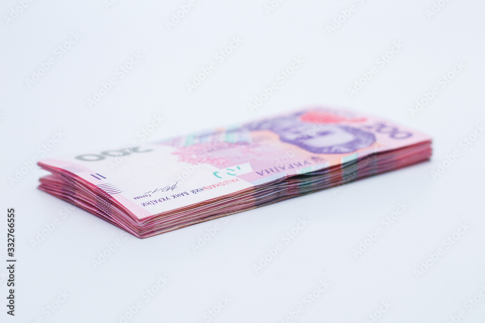 A lot of new banknotes in denominations of 200 Ukrainian hryvnias isolated on a white background with shadow. European money exchange. Ukraine currency. Selective focus A lot of new banknotes in denominations of 200 Ukrainian hryvnias isolated on a white background with shadow. European money exchange. Ukraine currency. Selective focus