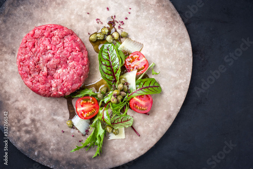 Foto Gourmet tartar raw from beef fillet with lettuce, tomatoes and parmesan with cap