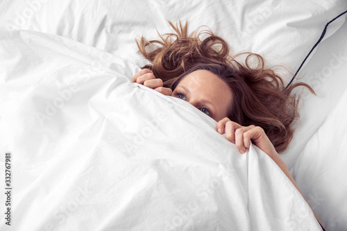 Frau unter Bettdecke versteckt