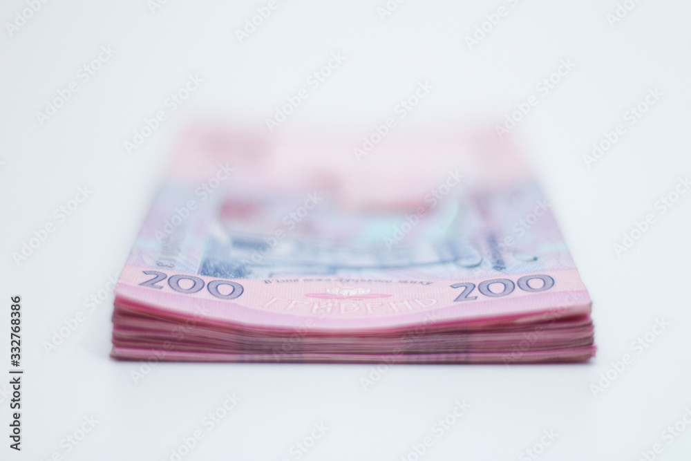 A lot of new banknotes in denominations of 200 Ukrainian hryvnias isolated on a white background with shadow. European money exchange. Ukraine currency. Selective focus A lot of new banknotes in denominations of 200 Ukrainian hryvnias isolated on a white background with shadow. European money exchange. Ukraine currency. Selective focus