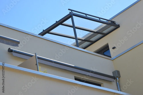 Modernes Glasdach mit Stahlrahmen über einer Dachterrasse auf einer neugebauten Flachdach-Mehrfamilienwohnanlage photo