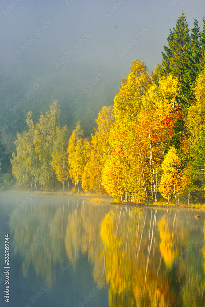 Autumn landscape in the mountains with trees reflecting in the water at St. Ana's lake, Romania Autumn landscape in the mountains with trees reflecting in the water at St. Ana's lake, Romania