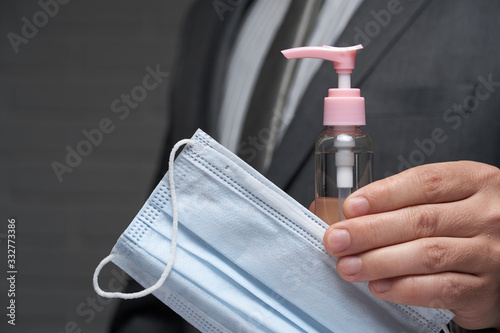 a man demonstrates a protective face mask for antivirus individual protection and bottle of sanitizer liquid- healthcare and medicine concept, prevention tips photo