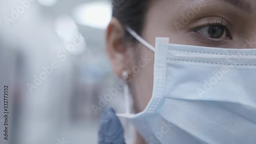 Closeup of nurse fixing mask in corridor.