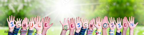Children Hands Building Colorful German Word Schule Geschlossen Means School Closed. Sunny Green Grass Meadow As Background photo