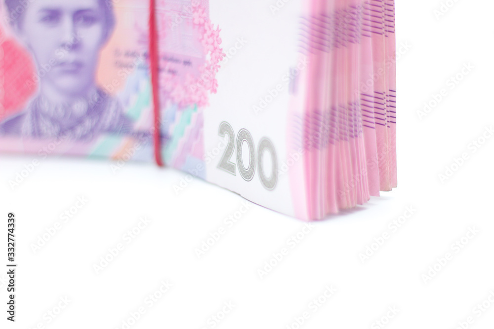 A lot of new banknotes in denominations of 200 Ukrainian hryvnias bandaged with an elastic band isolated on a white background with shadow. European money exchange. Ukraine currency. Selective focus A lot of new banknotes in denominations of 200 Ukrainian hryvnias bandaged with an elastic band isolated on a white background with shadow. European money exchange. Ukraine currency. Selective focus