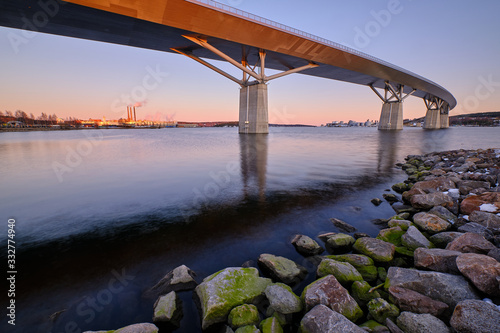 Big bridge going over a cove with stones foreground and a city in the background photo