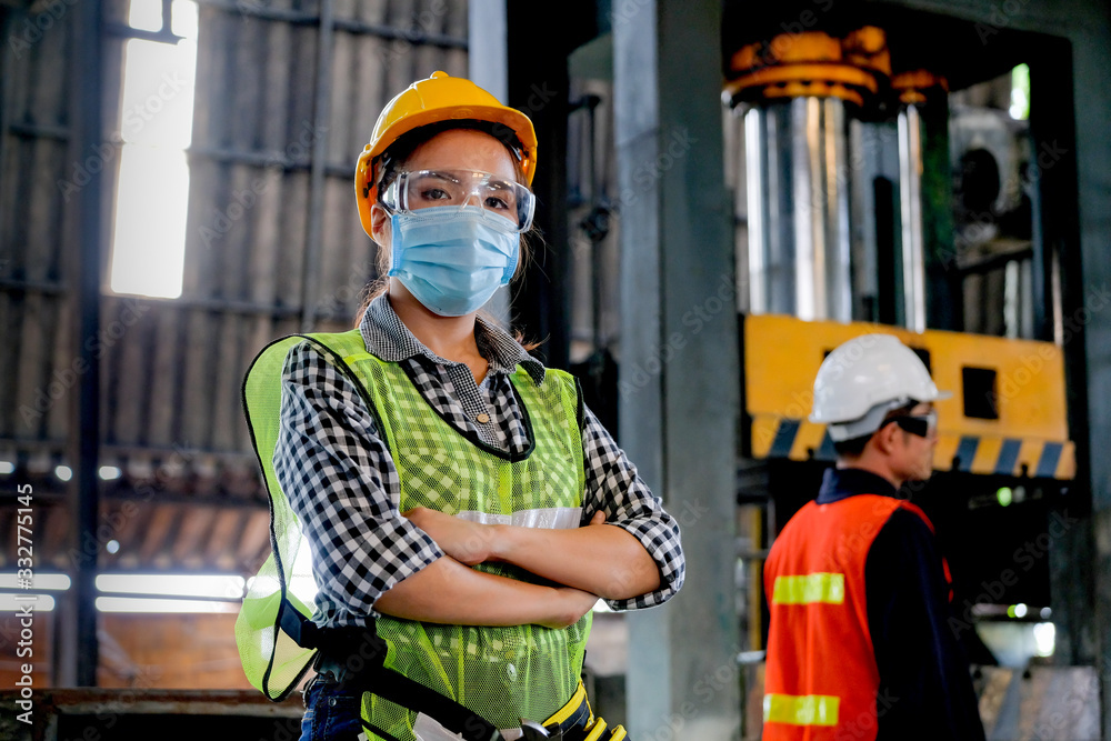 Factory woman engineer worker or technician with hygienic mask stand with confident action with her co-worker in workplace. Concept of good industrial system for better manufacture business. - obrazy, fototapety, plakaty 