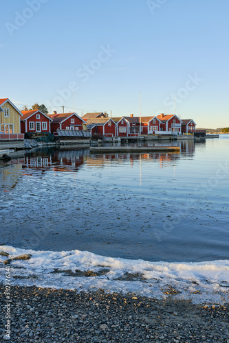 Small red cottages by the sea with ice on the beach in the foreground