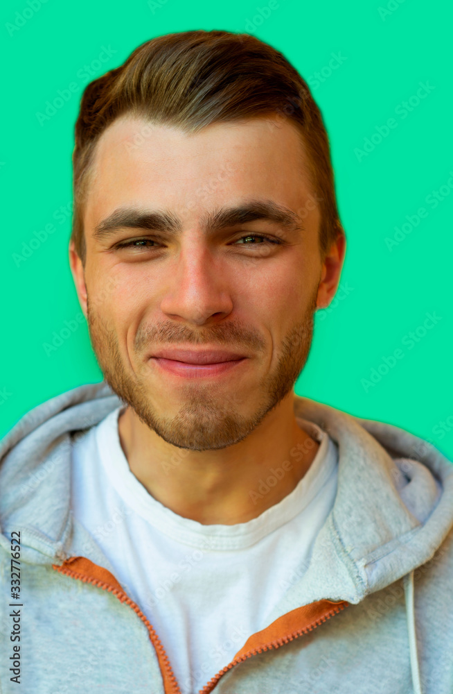 Fototapeta premium young hipster with a beard is smiling and looking at the camera on a neo mint color wall background.