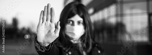 Wide angle closeup of young girl shows hand sign stop no to coronavirus epidemic pandemia originated at China. Covid-19 virus, nCov2019. Dramatic portrait of girl is against virus illness quarantine. photo