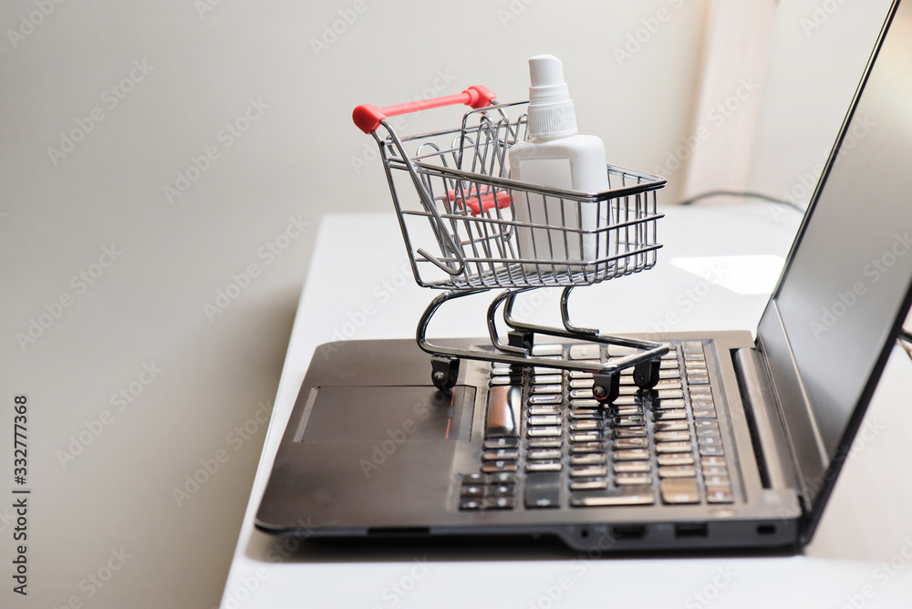 Conceptual photo with miniature shopping-cart and antiseptic. Safety internet shopping.