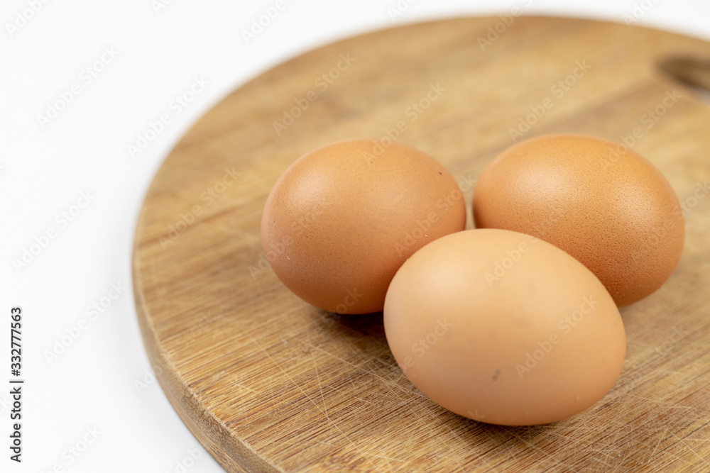 Three Chicken Eggs Isolated Above Roung Wooden Board Three Chicken Eggs Isolated Above Roung Wooden Board