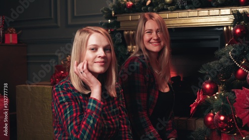 Two blondes in red shirts decorate the Christmas tree for the New Year or Christmas.