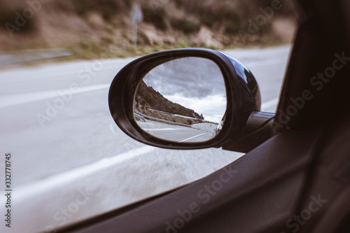 Oval mirror car reflecting an empty road with storm rainy clouds photo