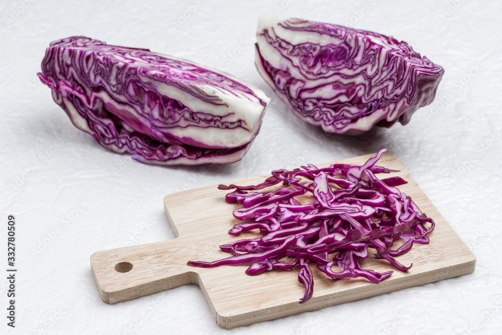 Halved red cabbage, sliced cabbage on cutting board.