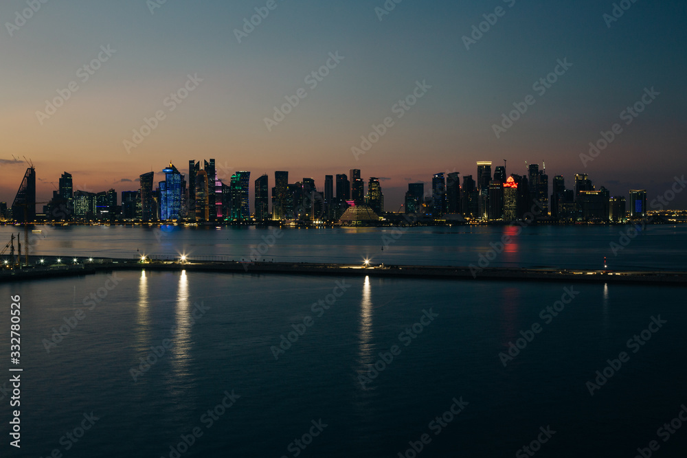 Fototapeta premium Panoramiczny nocny widok na drapacze chmur miasta Doha od strony morza
