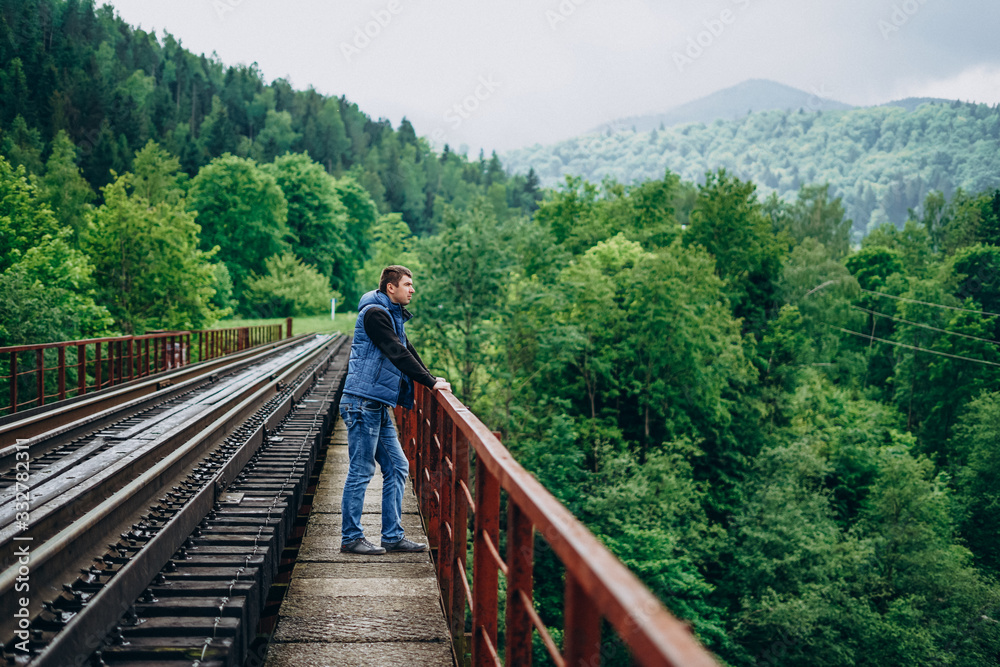 Young man on railway track on forest background. The observation deck.